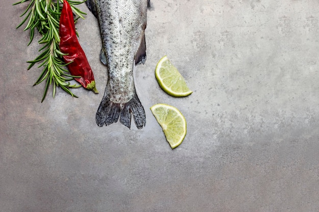 Foto coda di pesce trota cruda con ramoscelli di rosmarino, limoni e pepe