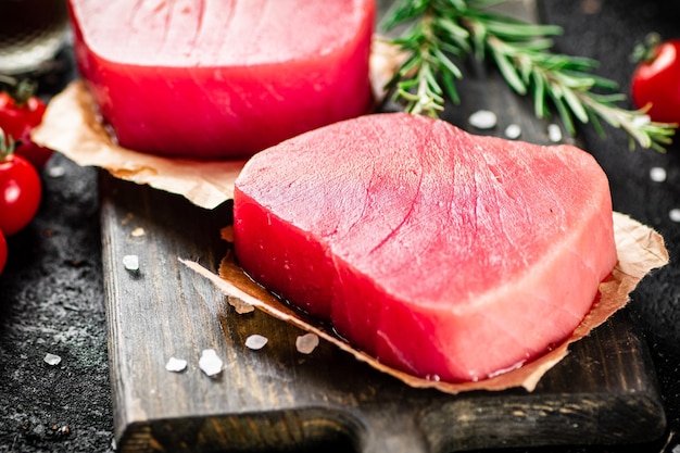 Foto tonno crudo su un tagliere con pomodori e rosmarino