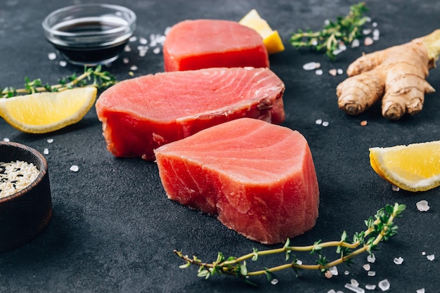 Raw tuna fillet steak with thyme lemon and ginger Seafood on a black stone