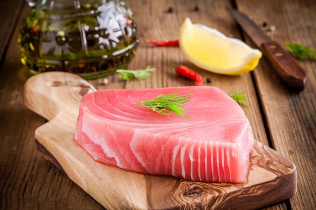 Raw tuna fillet with dill lemon and olive oil on rustic background