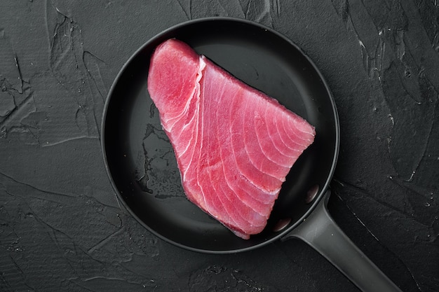 Сырой стейк из тунца, набор свежего филе красного тунца, на чугунной сковороде, на черном камне