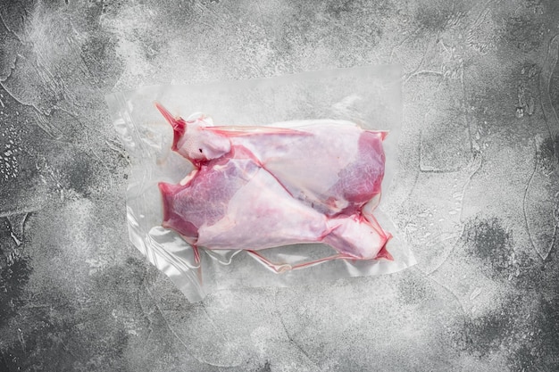 Foto coscia di tacchino cruda in confezione di plastica sottovuoto, vista dall'alto piatta, con spazio per la copia per il testo, su sfondo grigio tavolo in pietra