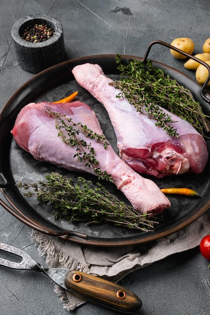 Raw turkey drumsticks with thyme pepper set on gray stone table background