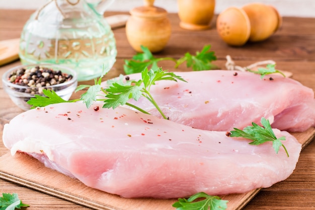 Raw turkey fillet in spices and herbs on a cutting board on a wooden table