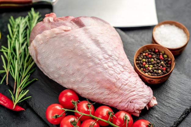 raw turkey leg with rosemary on stone table