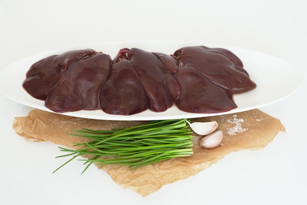 Raw turkey liver on a white plate Chicken entrails Green chives onions