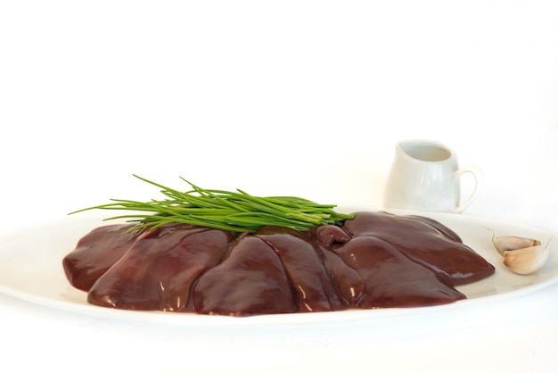 Raw turkey liver on a white plate Chicken entrails Green chives onions