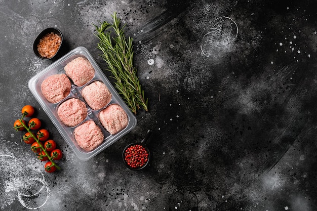 Raw turkey meatballs in plastic disposable tray set, on black dark stone table background, top view flat lay, with copy space for text