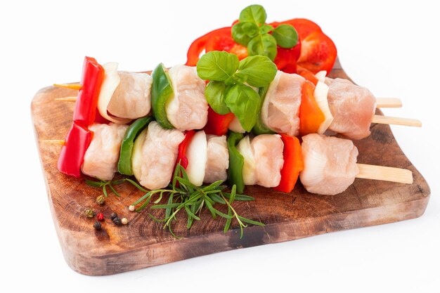 Photo raw turkey skewers with vegetablespeppersonions white backgroundskewers with pieces of raw meatred a