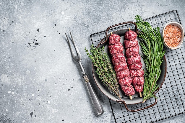 Raw Turkish Urfa kebab decorated with herbs spices and meat fork Gray background Top view Copy space