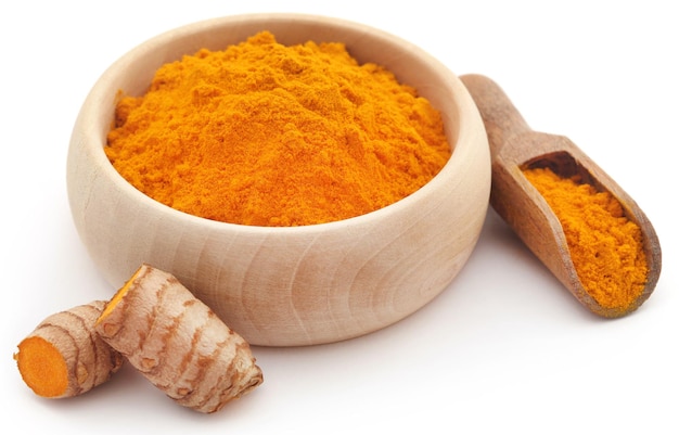 Raw turmeric with powder in a wooden bowl