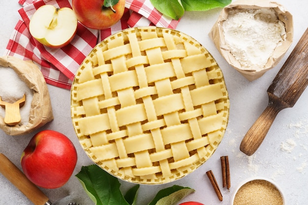 Сырой невыпеченный яблочный пирог с инструментами и ингредиентами для приготовления