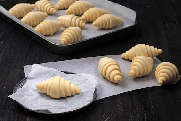 Raw Unbaked Croissant on Baking Paper in Rustic PlateOver Black Wooden Table