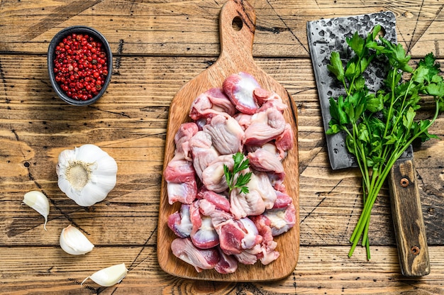 Raw uncooked chicken gizzards, stomach on a cutting board.