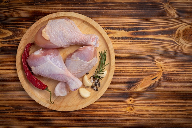 Raw uncooked chicken legs on the dark wooden surface.