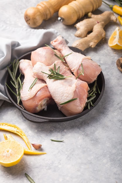 Raw uncooked chicken legs on wooden board with herbs for cooking