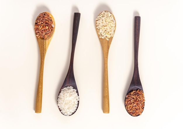 Raw and uncooked rice assortment in wooden spoon on white background Place for text Top view