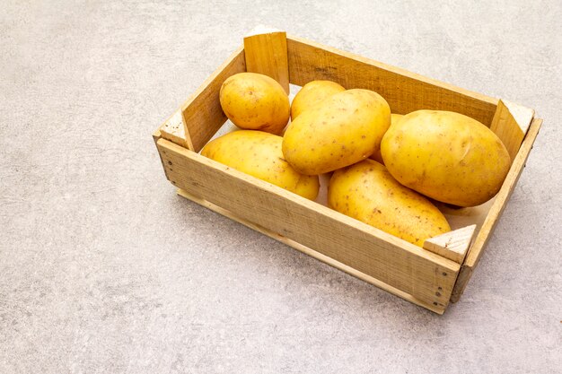 Raw unpeeled young potatoes in a wooden crate