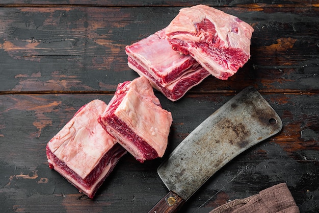 Set di carne di costolette di vitello crudo di vitello e vecchio coltello da macellaio, su un vecchio tavolo di legno scuro