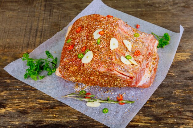 Raw veal ribs with spices on parchment paper.