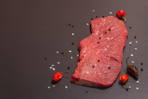 Photo raw veal steak with spices rosemary and chili pepper a trendy hard light dark shadow