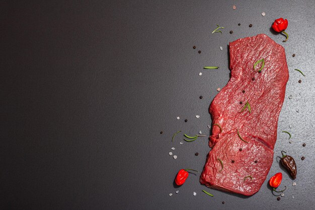 Raw veal steak with spices rosemary and chili pepper A trendy hard light dark shadow