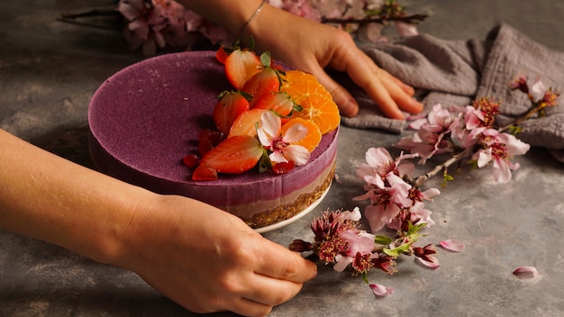 Foto torta vegana cruda con frutta e semi, decorata con fiori