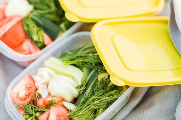 Verdure crude pomodori, cetrioli, cipolle e aneto in contenitori di plastica. avvicinamento. cibo sano, dieta