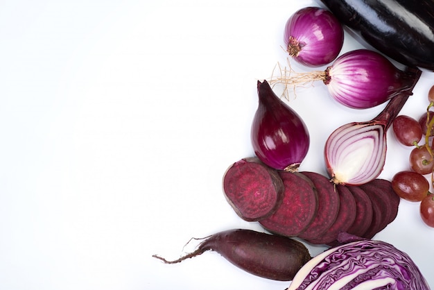 Raw violet vegetables and fruit on white background.