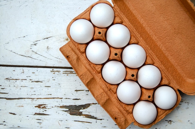 Raw white chicken eggs in egg open box top view.