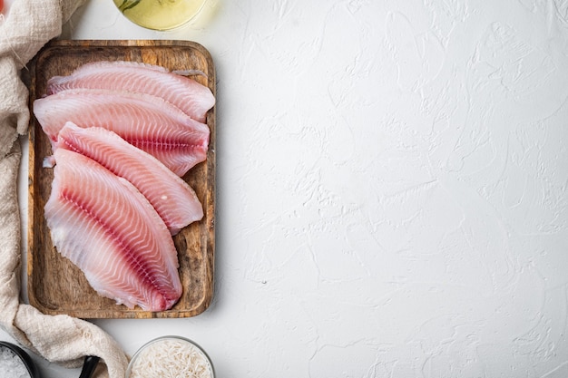 生の白身魚のティラピア、バスマティライスとチェリートマトの材料、白いテーブル、上面図