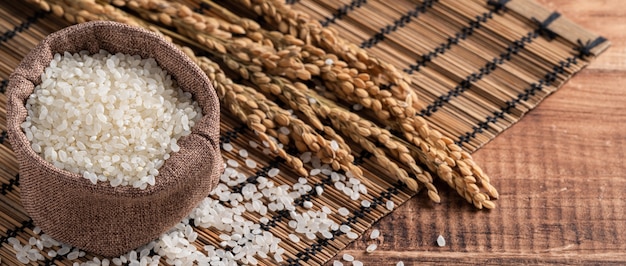 Raw white polished milled edible rice on wooden table background in a bowl, organic design concept.