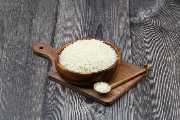 黒い背景の生白米 長い未調理の米 木製の皿 自然有機食品 伝統的なアジア穀物文化