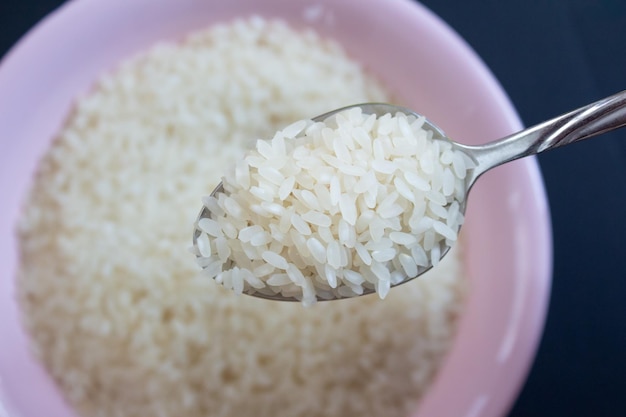 Raw white rice in metal spoon. Top view.