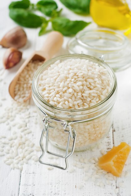 Raw White rice variety Arborio for Italian risotto dishes in glass jar on white concrete or stone background