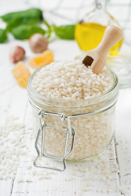 Raw White rice variety Arborio for Italian risotto dishes in glass jar on white concrete or stone surface. Selective focus. Copy space.