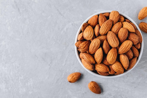 Raw whole almond in bowl on gray background Top view