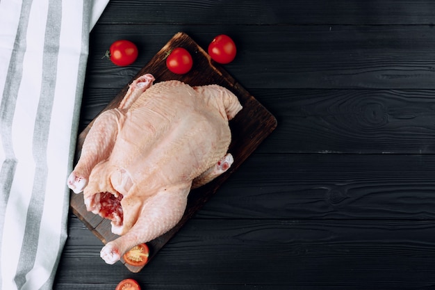 Raw whole chicken carcass on wooden cutting board close up