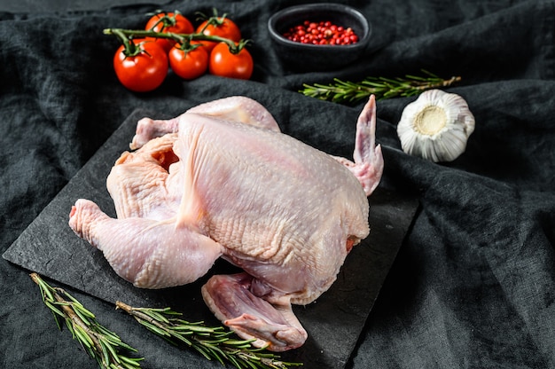 Raw whole chicken with rosemary and pepper