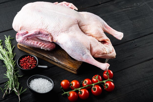 Photo raw whole duck meat on black wooden background.