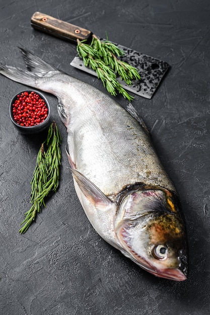 Raw whole fish silver carp with pink pepper and rosemary