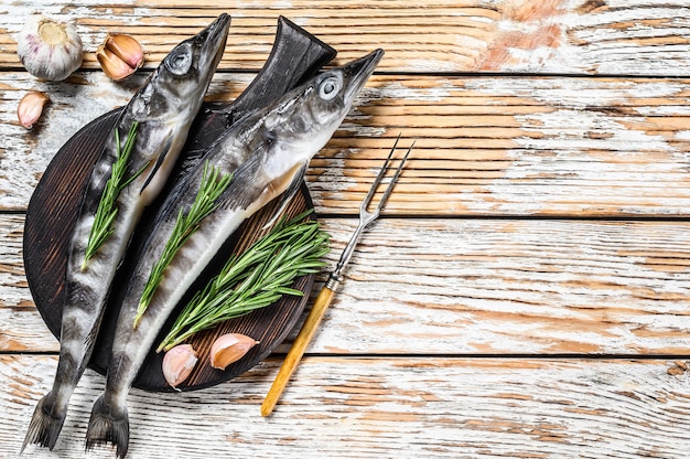 Raw whole icefish with herbs. White Wooden background. Top view. Copy space.