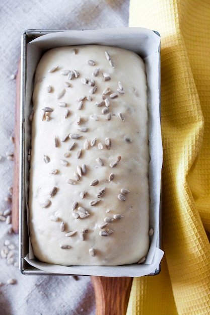 Raw yeast dough in tin form, ready for baking bread with sunflower seeds