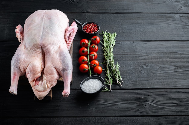 Raw young goose meat on black wooden table,.