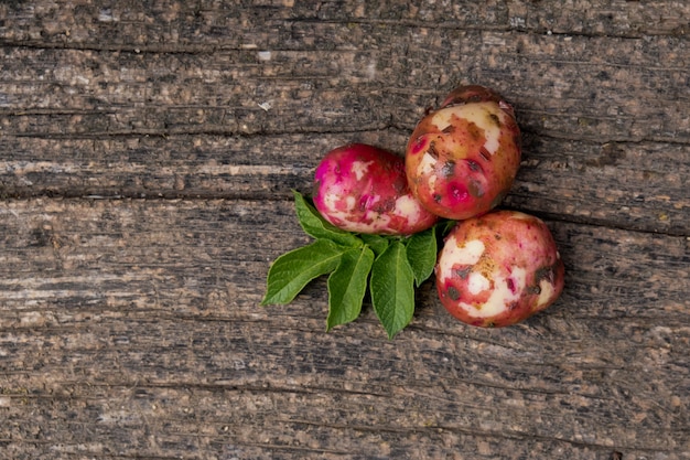 Raw young potatoes with foliage on a wooden.