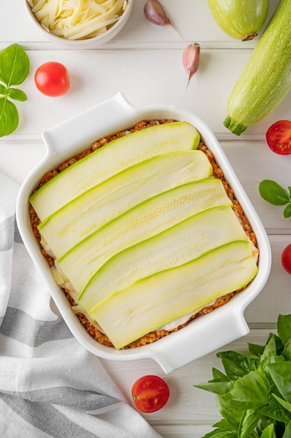 Raw zucchini lasagna with sauce bolognese in a baking dish Healthy food Top view Selective focus