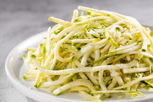 テーブルの上の皿に生のズッキーニの麺