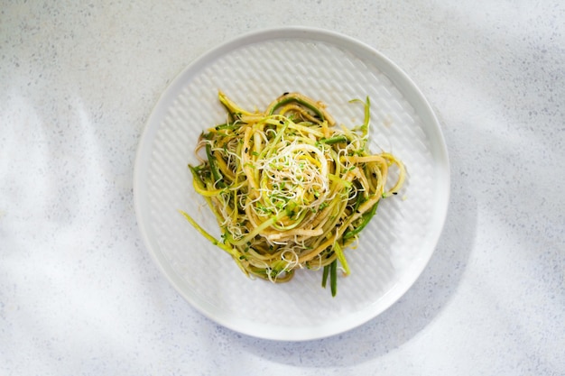 Raw zucchini noodles in on the plate top view on the white