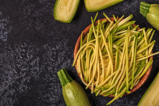 Raw zucchini pasta on dark surface