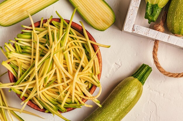 白い背景の上の生のズッキーニパスタ